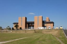 青空の下建つ茶色外壁の龍Q館の南側外観を遠目のアングルから撮影した写真