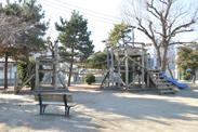木々に囲まれる公園内遊具の写真