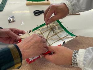 講師に教わりながら飾り凧の弓張りをしている様子