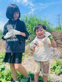 収穫したキュウリを持って笑顔の姉弟