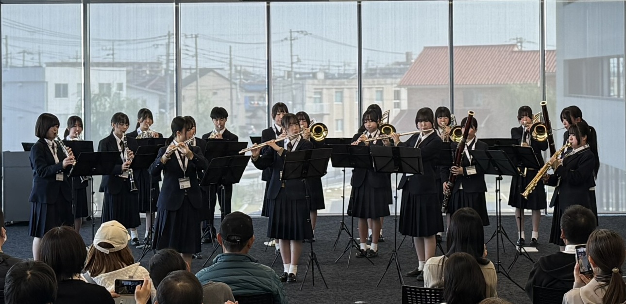 20人ほどの学生が座って吹奏楽を演奏する様子