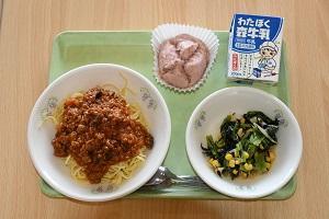 ボロネーゼ風パスタとサラダ、牛乳と蒸しパンが並んだ給食の写真