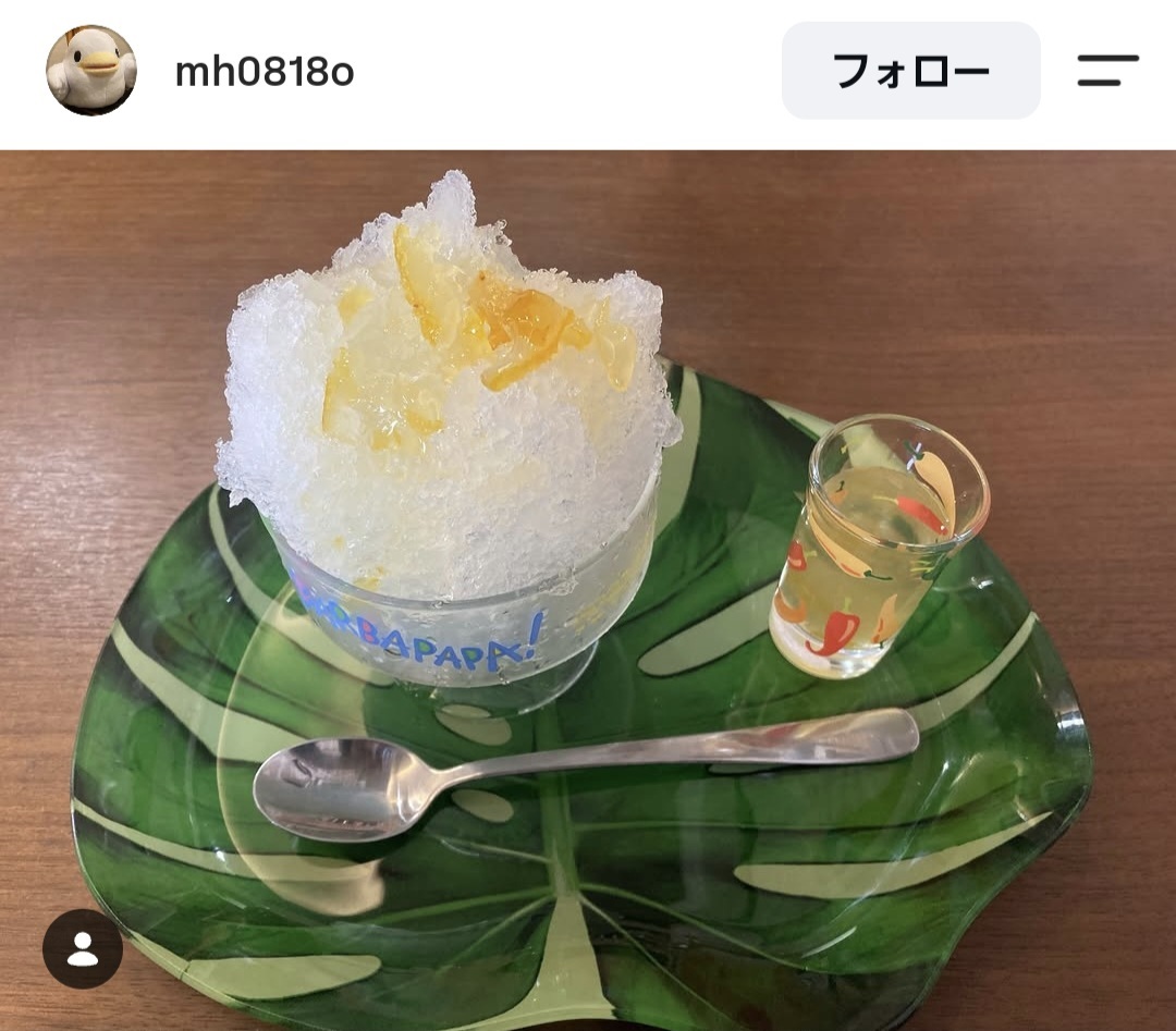 ゆずの皮を使ったシロップがかかったかき氷が緑色の葉っぱを模したお皿に乗っている様子を上から撮影した写真。