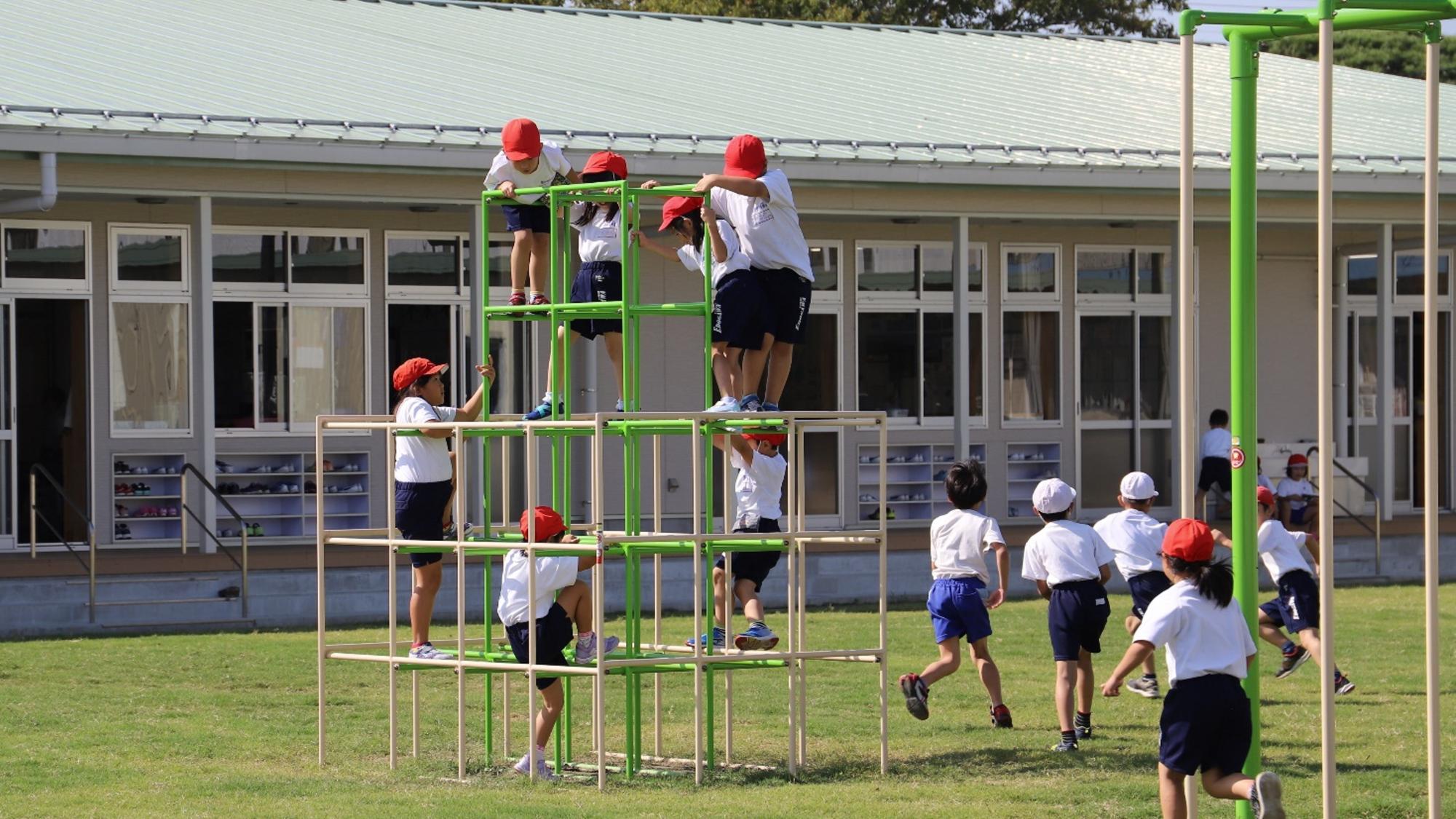 紅白帽子を被り体育着を着た児童たちがジャングルジムで遊んでいる写真