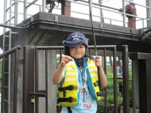 ライフジャケットを着用して釣った魚を持ち笑顔を向ける子どもの写真