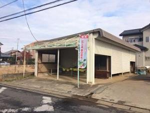 入り口が大きくあいたガレージのような建物の横に、のぼりが立っている写真