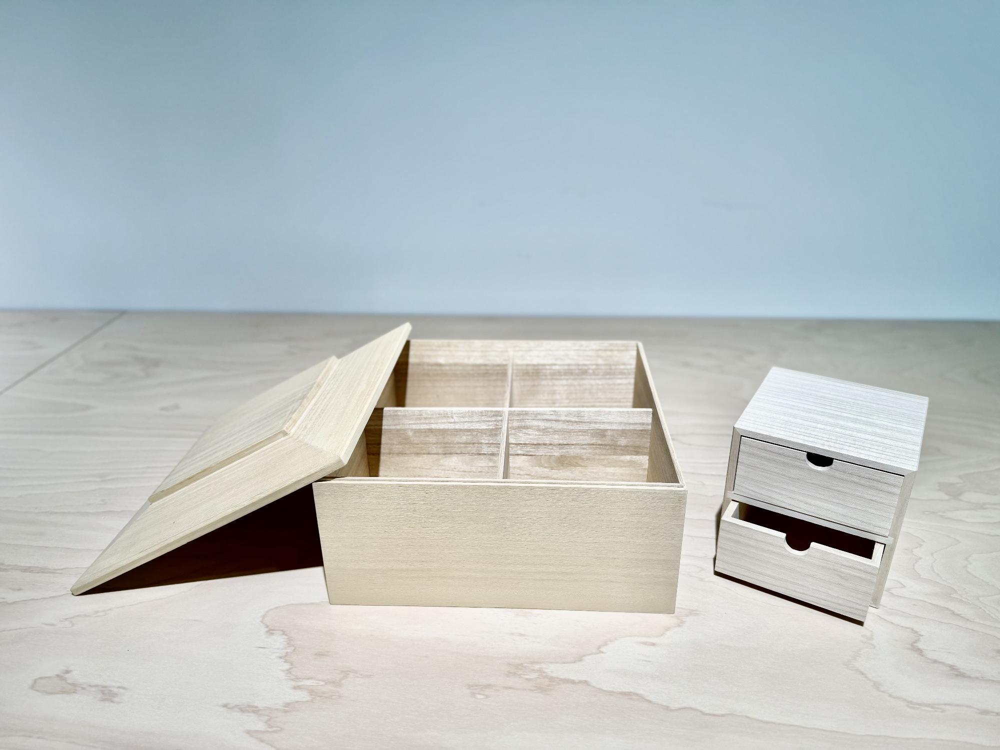 ふたが開いた淡い木目の桐箱と小さな2段の桐箱が写った写真