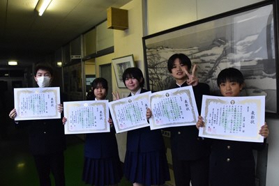 オリジナル給食メニューコンテストの表彰状を手に笑顔を浮かべる生徒たち