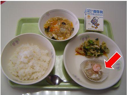 お盆に載せられた給食のえびしゅうまいのお皿を矢印で示した写真