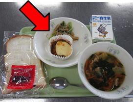 お盆に載せられた給食のなすのミートグラタンのお皿を矢印で示した写真