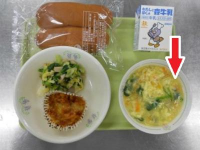 お盆に載せられた給食の卵スープを赤い矢印マークで示している写真