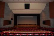 えんじ色の座席シートがステージに向かって連なる庄和地区公民館大ホールの写真