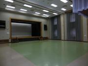 緑と茶色のフロアが特徴的な幸松地区公民館講堂の写真