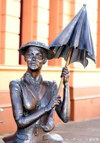 メリーボロー地区のメアリー・ポピンズの記念館前にある、メアリー・ポピンズ像の上半身の写真。閉じた傘を両手で持って掲げている。
