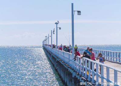 珊瑚海に面したウランガン桟橋の片側に寄って並んで釣りをしたり海を見ている観光客たちの写真