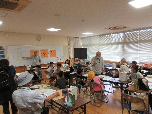 囲碁教室で講師の説明を児童が聞いている写真