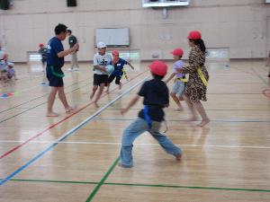 体育館で児童がタグラグビーをしている写真