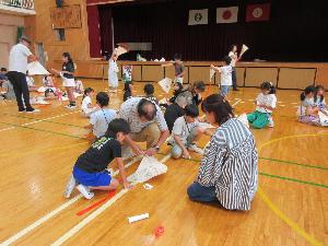 体育館で児童が凧作りをしている写真