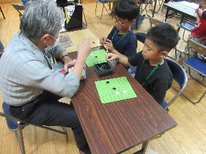 囲碁教室で児童が囲碁の指導を受けている写真