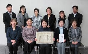 表彰状を囲んで人々が並んでいる埼玉・教育ふれあい賞受賞の様子の写真
