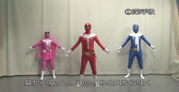 ピンク、赤、青のコスチュームを着たヒーローたちが、並んで体操をしている写真