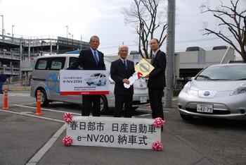 今回納車された電気自動車e-NV200と日産リーフの前で3人で撮られた記念写真