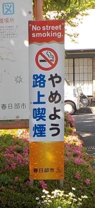「やめよう路上喫煙」と書かれた立て看板が、植え込みの中に設置されている写真