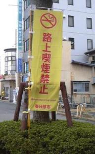 路上喫煙禁止と書かれた黄色いのぼりが、植え込みの中に設置されている写真