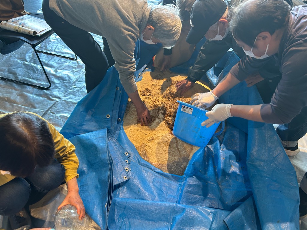 堆肥づくり講習会で米ぬかと籾殻を混ぜる様子