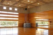 暖かい木製の木と床に窓から光が差し込む多目的ホールの写真