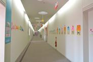 両側の壁に色とりどりのキャラクターが貼ってある白い廊下の写真