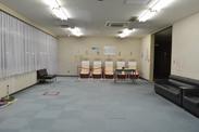 灰色の絨毯が敷かれて広々とした様子の機能回復訓練室の写真
