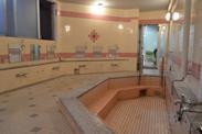ピンク色のタイルで構成された大浴場の写真