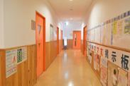 オレンジの扉と光沢のある木製の廊下が奥に続いている写真