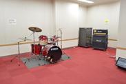 赤いじゅうたんにドラムのセットとアンプが設置されている写真