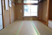 木と畳の暖かい色合いの和室に窓から光が差し込んでいる写真