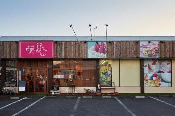 木板の壁とピンクの看板が特徴的な店舗外観の写真