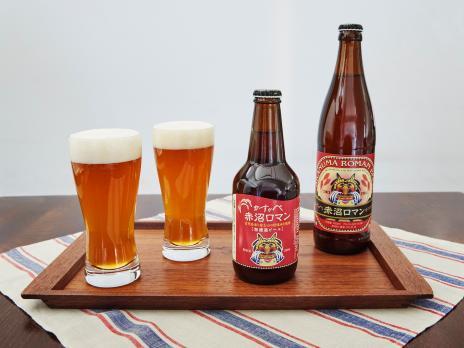 ラベル入りの瓶とビールが注がれているグラスの赤沼ロマンビールの写真