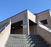 卵色の外壁と灰色の階段のコントラストが特徴的な武里図書館外観の写真