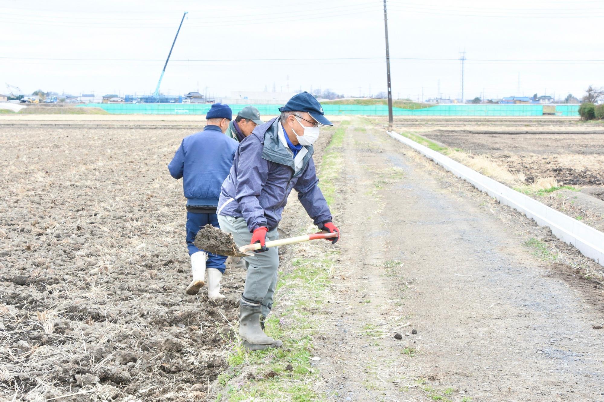 シャベルいっぱいの土を運ぶ様子