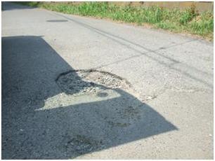 コンクリートの道路に浅く陥没している穴がある様子の写真