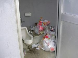 ゴミ袋2袋分の家庭ごみが捨てられている公園のトイレの写真