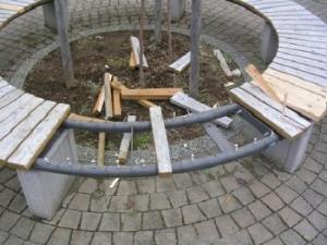 ベンチ部分の木材がはがされて壊されている公園のベンチの写真