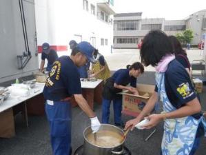 消防署敷地内にて炊き出し訓練のため食事を作る消防隊員の写真