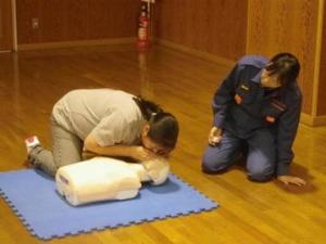 応急手当指導にあたる女性消防団員と、人工呼吸訓練を行う女性の写真