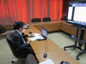 モニターに向かいパソコンと資料を広げながらミーティングに参加する男性の写真
