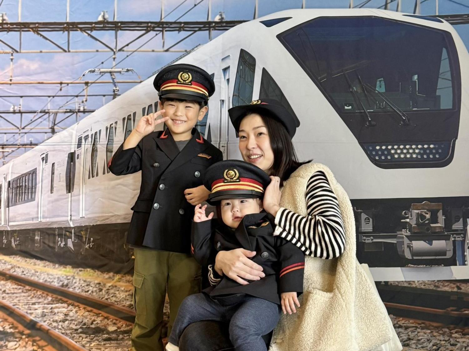 2名のこどもが駅長服を着用し母親と記念撮影する様子