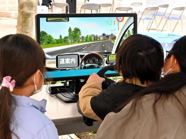 こどもがハンドルを握りドライブゲームをする様子