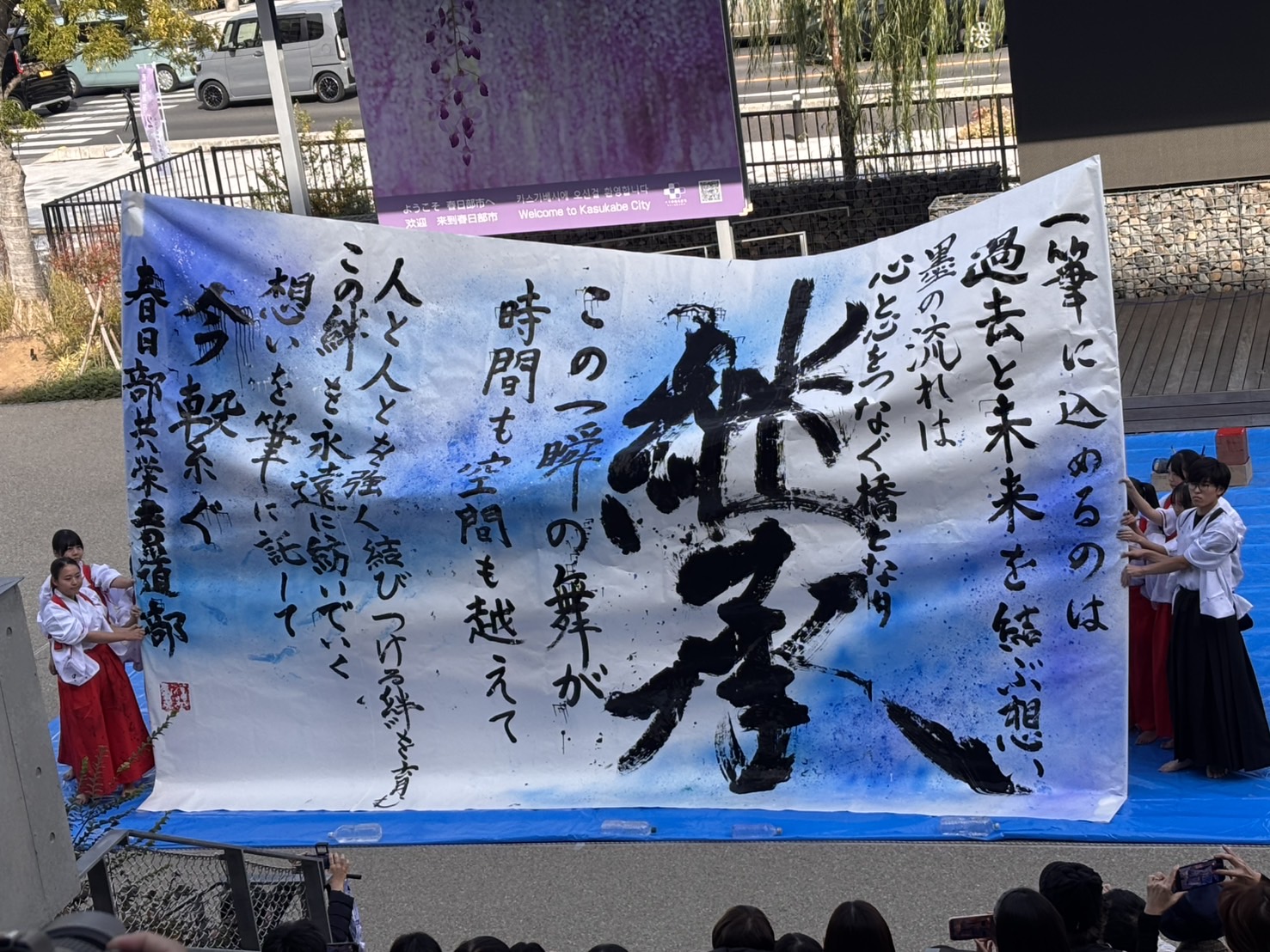大きな半紙に大きな筆で文字を書く様子
