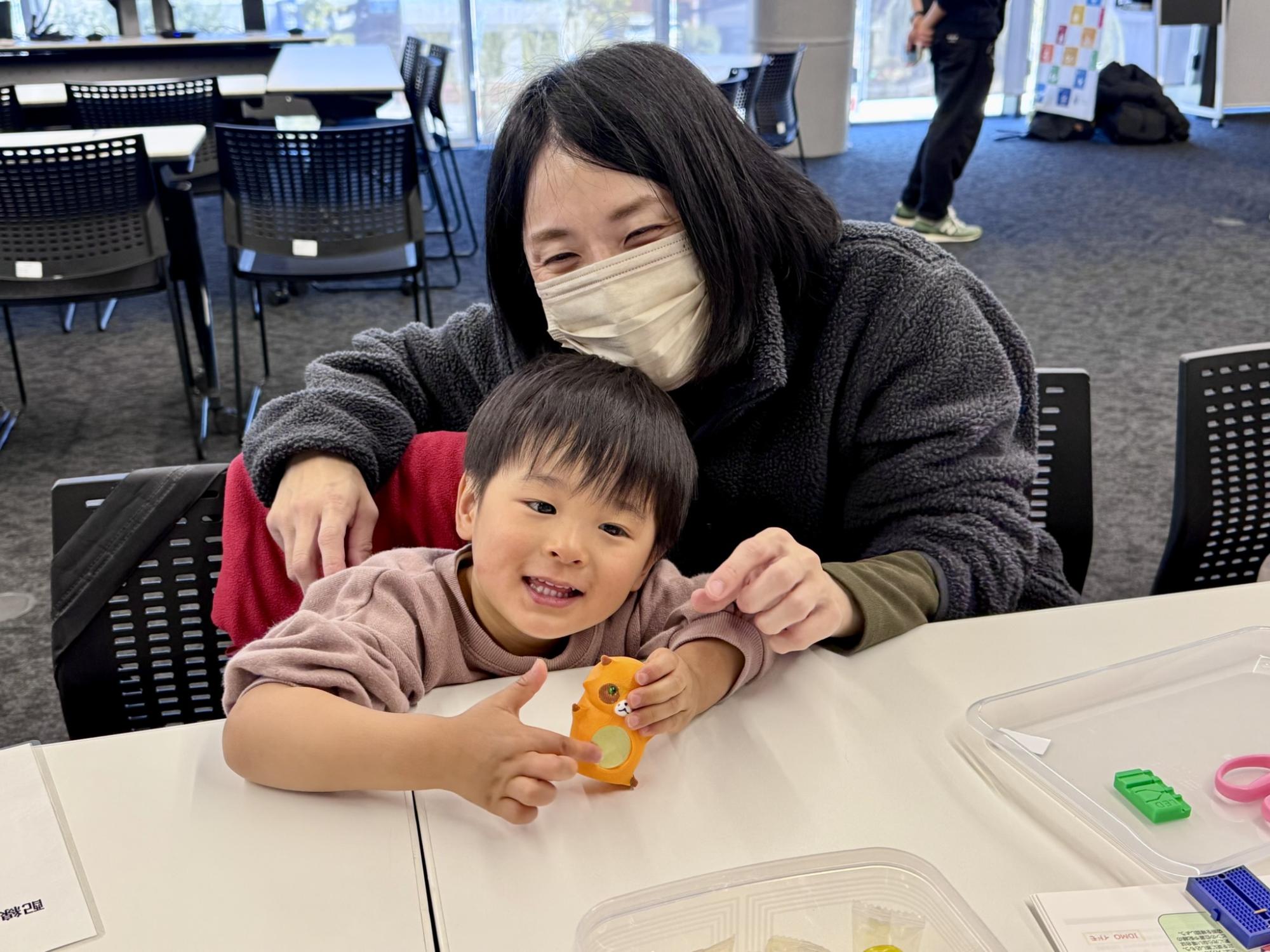 電池レスで光る！ぽんぽこピカ助を作ろうで制作したおもちゃを持って記念撮影する様子